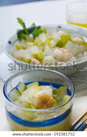 Two containers filled with shrimp, broth and vegetables.