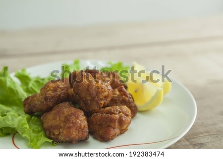 A plate full of meat, lettuce, and lemon wedges.