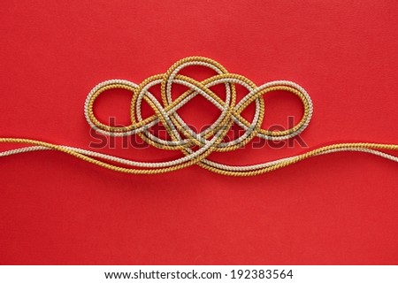 Silver and gold string tied in an intricate knot.