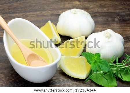 A oval shaped dish with liquid in it and some lemons and garlic cloves.