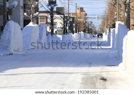 A long snow covered street with tall snow banks.