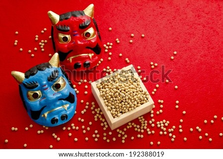 Two differently colored devil masks next to pellets in a box.
