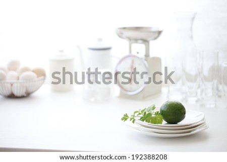 A lime on plates with a scale and eggs with other dishes in the background.