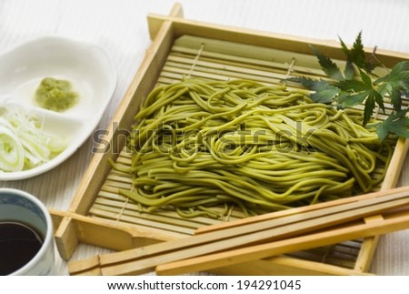 A square platter with some green noodles on it.