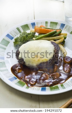 A meat patty with gravy, mushrooms, and vegetables.