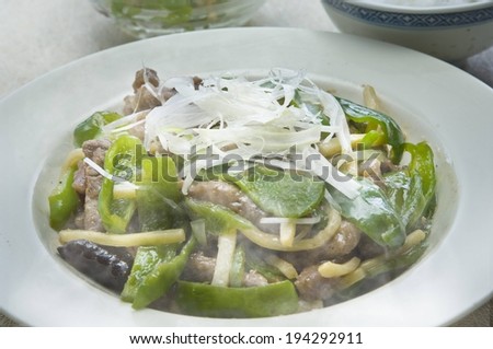 A plate full of noodles, meat and peppers.
