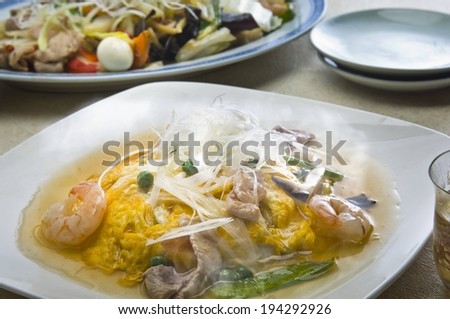 A steaming plate of seafood in broth with vegetables.