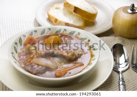 Bread on a plate, and a bowl of vegetable soup.