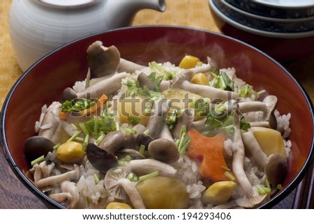 A steaming bowl of rice and vegetables and a pot of tea.