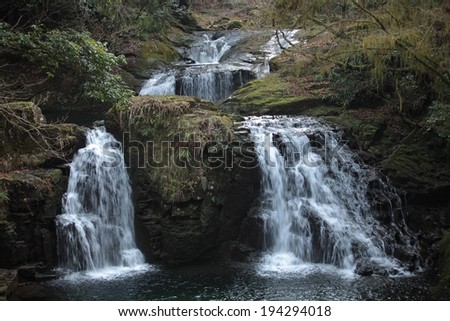 Water flowing down a hill and two waterfalls into a body of water.