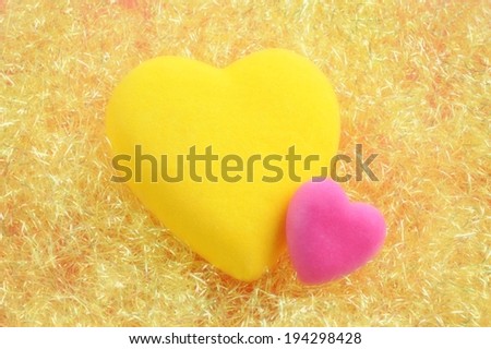 A pink and yellow heart on a bed of shredded paper.