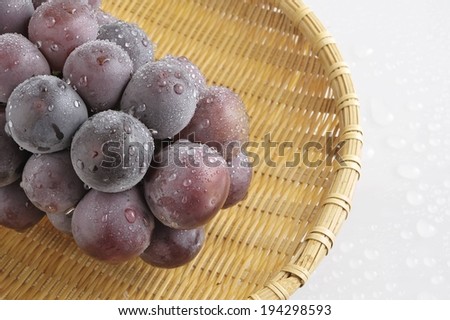 A bunch of wet grapes inside of a wicker basket.