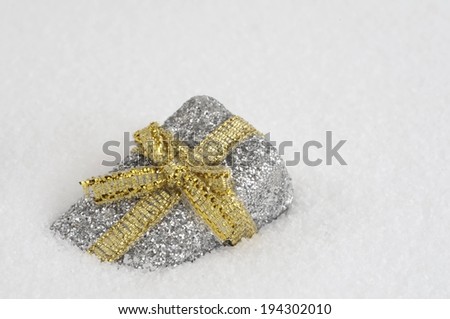 A silver metallic gift wrapped in gold metallic ribbon.