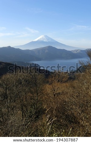 A large, distant mountain overlooking closer mountains, a lake, and a forest.