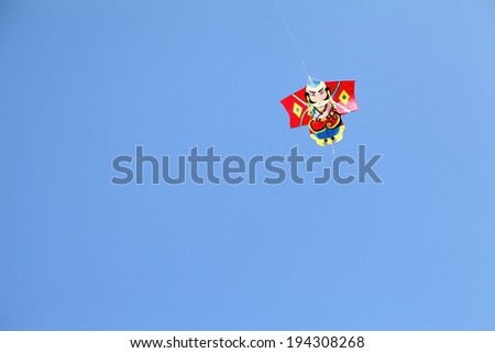 A single small red item hanging on a string against a blue sky.
