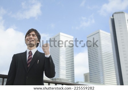 Businessmen shows the victory pose in front of a building