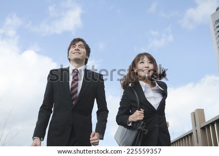 Business woman and business man are running through the front of the building