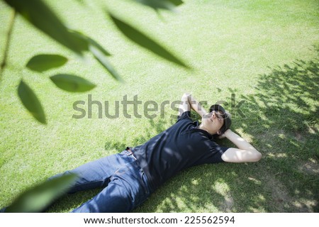Man lying down on lawn under tree shade