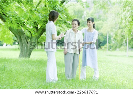 Helper and nurse and senior woman standing on the lawn
