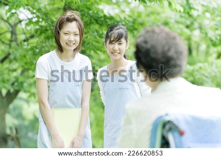 Two helpers greeting senior woman