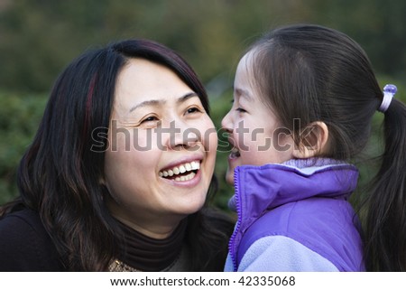 mother and daughter in a city park, laughing, shanghai, china