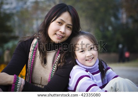 mother and daughter sitting in a city park, shanghai, china
