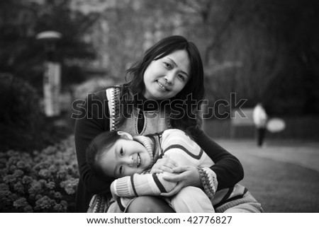 8-year old little asian girl resting on mother\'s knees in park, shanghai, china