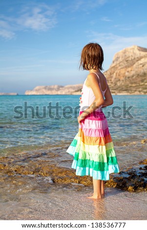Beautiful girl relaxing on vacation. She is holding the hem of her skirt and walks by the sea.