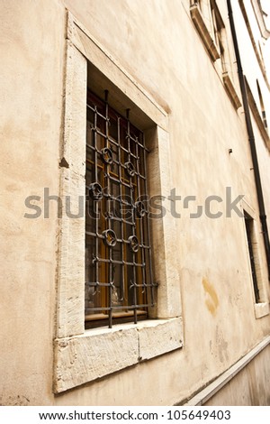 Side shot of a gated window on a tan, stone building.