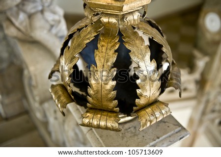 A decorative, gold and black base to a pillar of a Greek architecture.