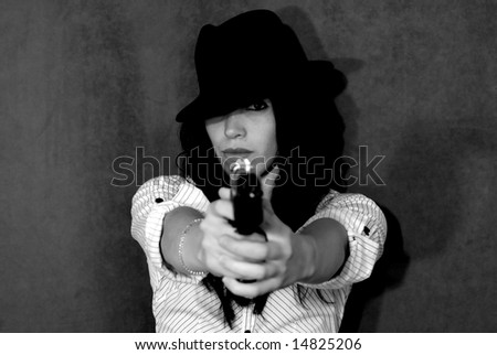 Gorgeous female model posing with a gun in a studio.