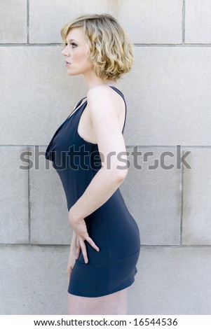 White woman in dress with hands on thighs looking to the right