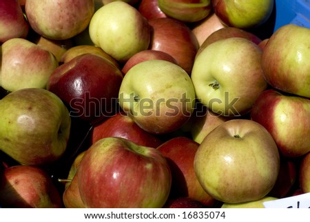 Group of apples at a farmers market on a sunny day.