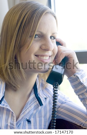 Shot of woman smiling at the camera while on the telephone