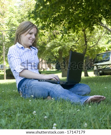 Young adult with no shoes on typing on her laptop