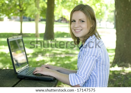 Girl sitting by tree while on laptop