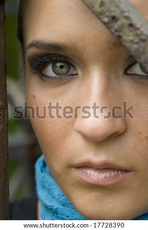 Face shot of a beautiful woman with green eyes and a turquoise scarf around her neck on a bright day