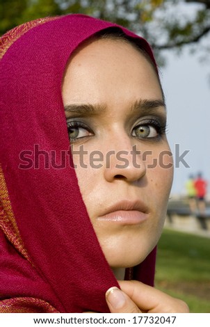 Olive skinned female with fuchsia headscarf looking at the camera