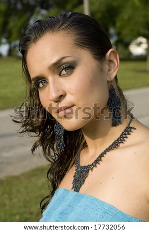 Pretty adult female with black and turquoise jewelry posing on a sunny day