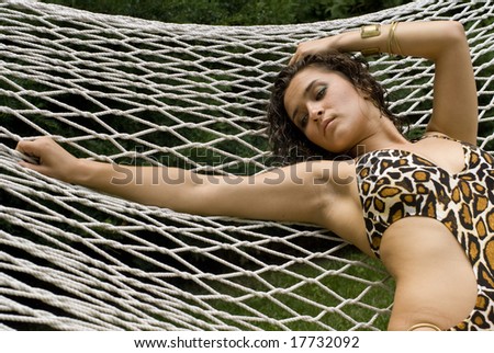 Sexy brunette stretched out in a white hammock on a sunny day