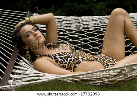 Beautiful Latina in animal print bathing suit laying in a white hammock on a sunny day