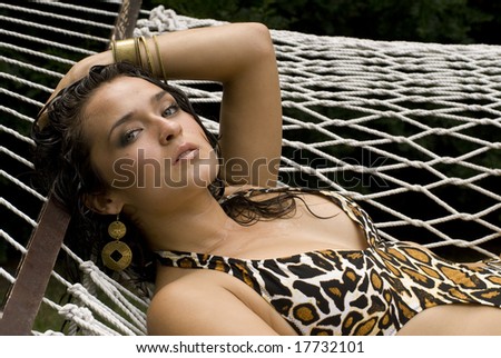 Close-up of sexy brunette with an animal print swimming sit in a white hammock