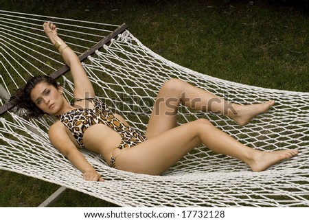 Wide angle shot of a pretty woman in bikini in a white hammock on a summer day