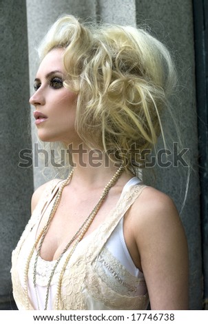 Tall fashion model in cream dress and big hair posing on a sunny day