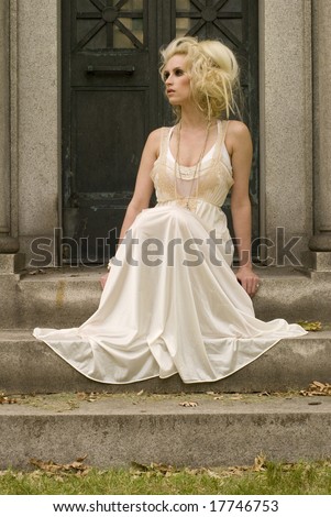 Tall woman in white dress sitting outside on the steps looking to the left
