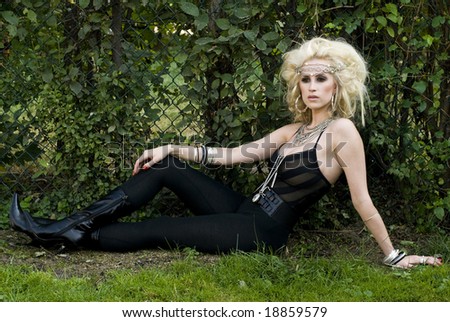 Model posing on the grass wearing black patent leather boots