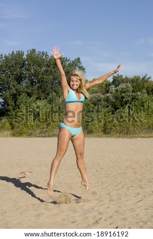 Blonde woman with lots of energy jumps in the sand on a sunny day