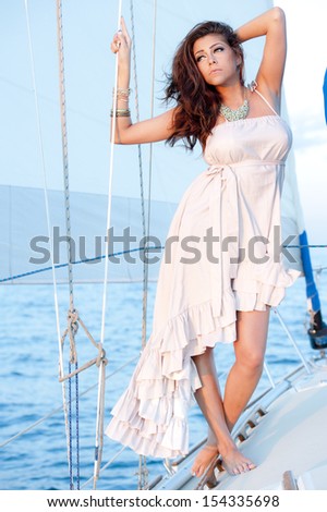 A beautiful, young, women in a side, high-low, white dress on a boat.