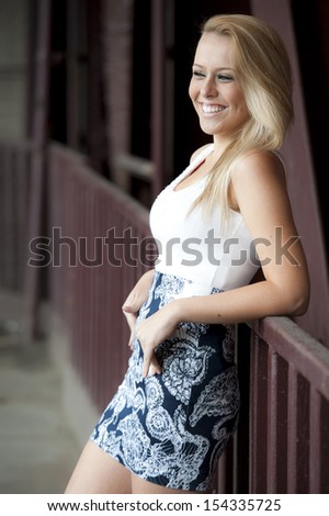 A happy, beautiful, young model smiling into the distance wearing a patterned blue skirt.