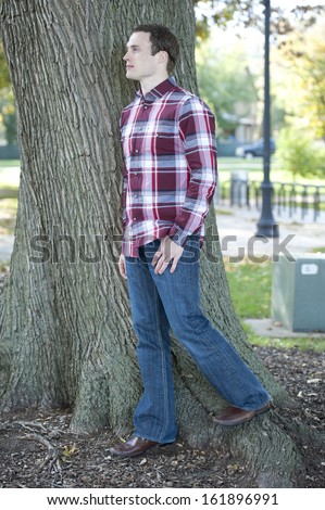 An attractive, fashionable and young male model posing outdoors on a sunny day looking left.